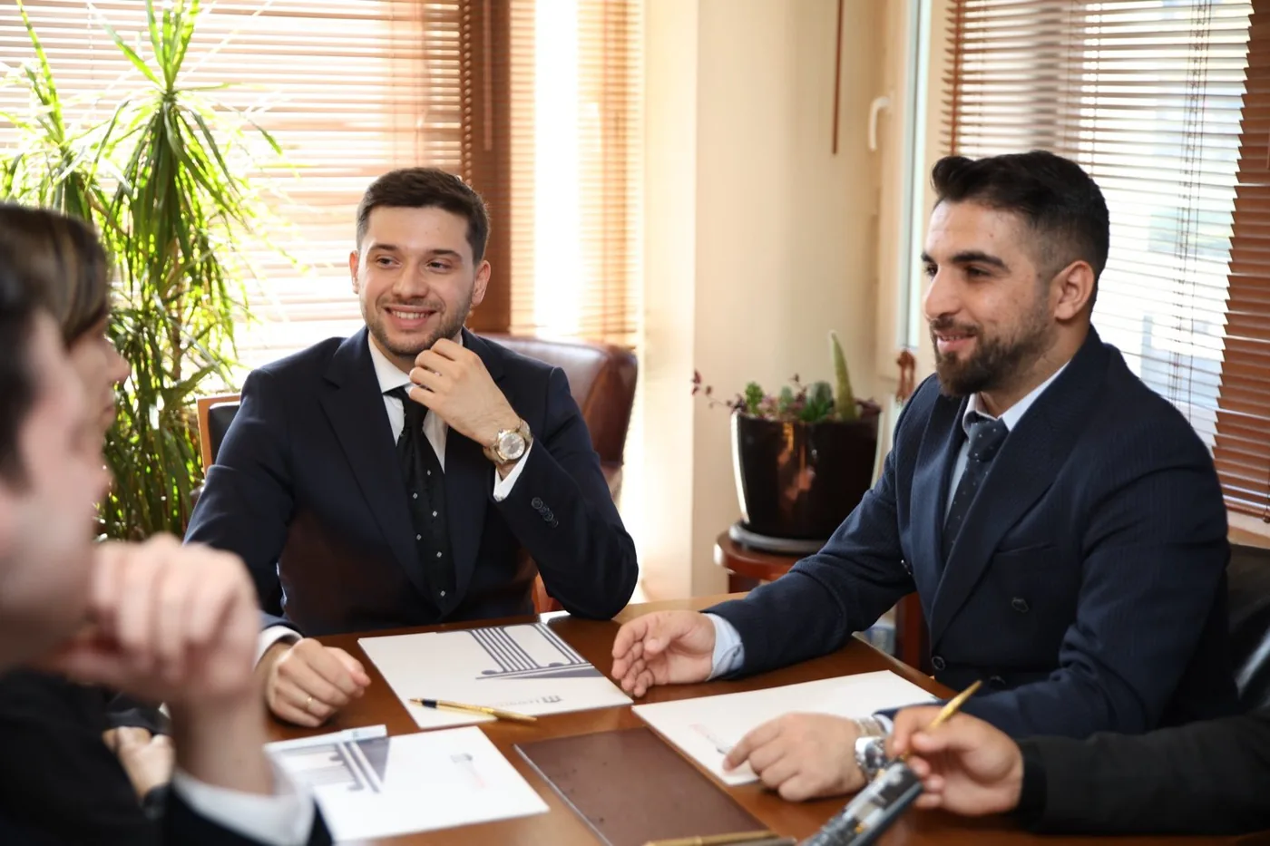 Kurucu ortaklar büroda bir toplantı masasında müvekkille görüşürken.